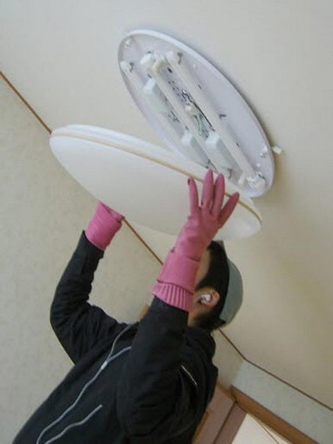 방 전등을 떼어내어 청소 중인 작업자